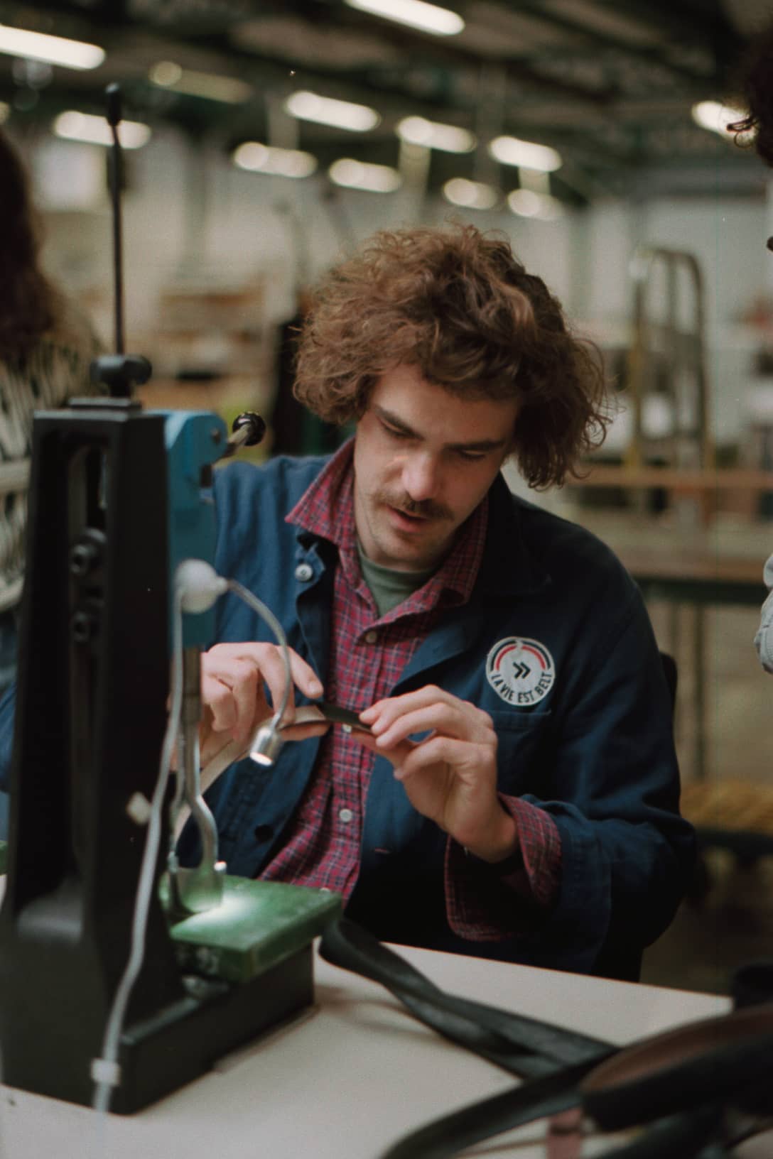 Un artisan travaille une ceinture en pneu de vélo