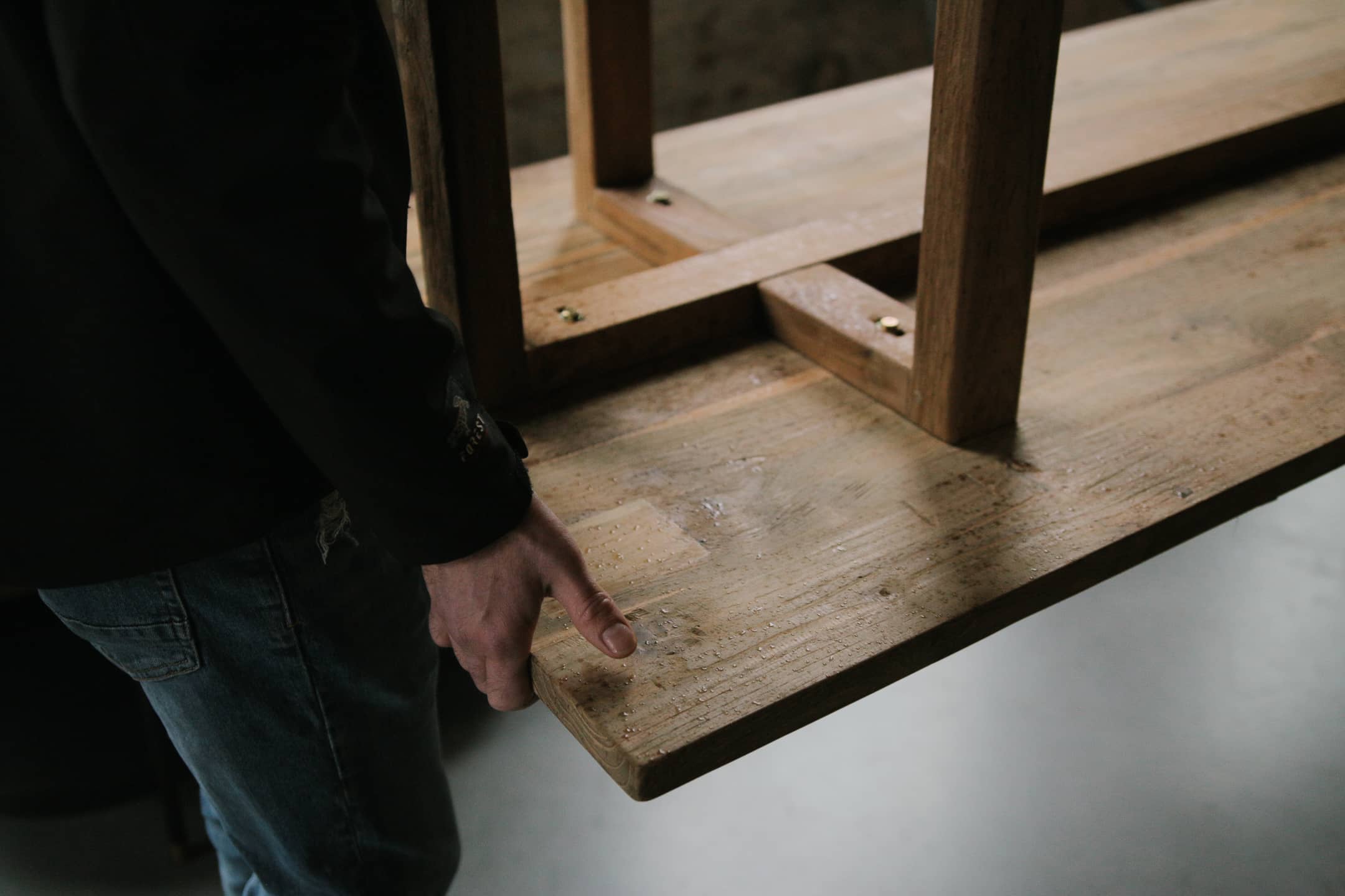 Un homme porte une table en bois massif pour la transporter